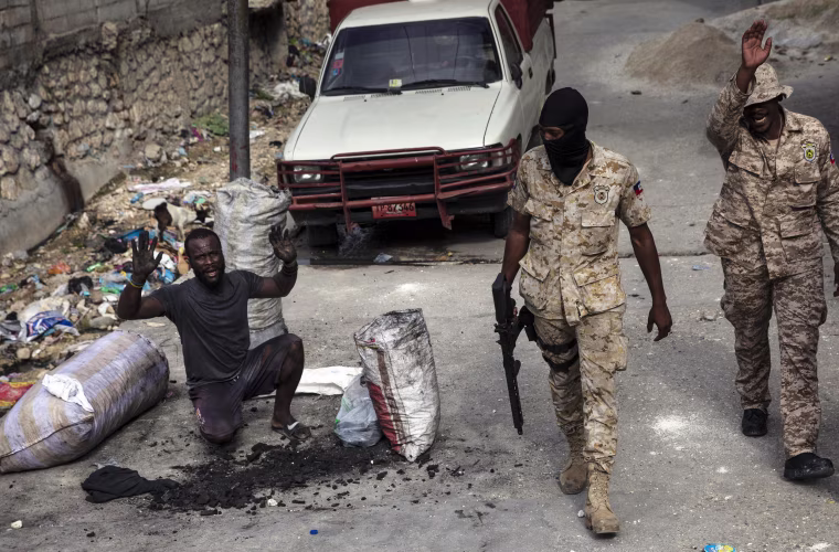 A man raises his arms to show his innocence as policemen patrol the streets in downtown in Port-au-Prince, Haiti, on Sept. 22, 2021, where residents have set up a barricade in protest after accusing police of killing a man during a raid.