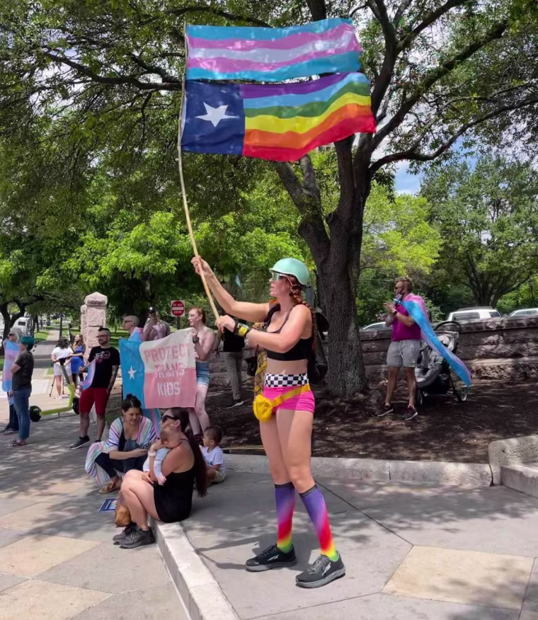 The Rev. Remington Johnson waves pride flags at a rally in Austin in May.