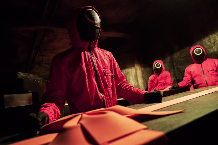 Masked staff handle boxes holding the dead bodies of contestants in the Korean survival drama "Squid Game" on Netflix.