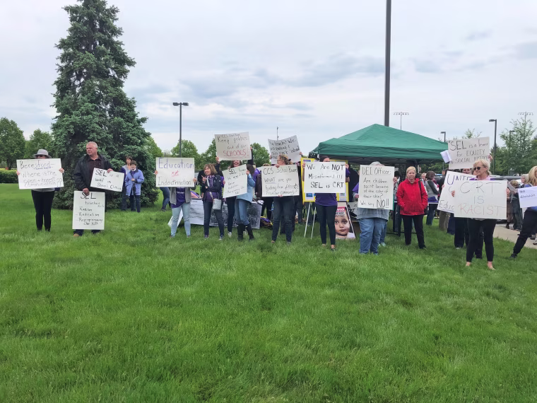 A crowd carrying signs protesting SEL gathers ahead of the Carmel Clay School Board meeting on May 17, 2021.