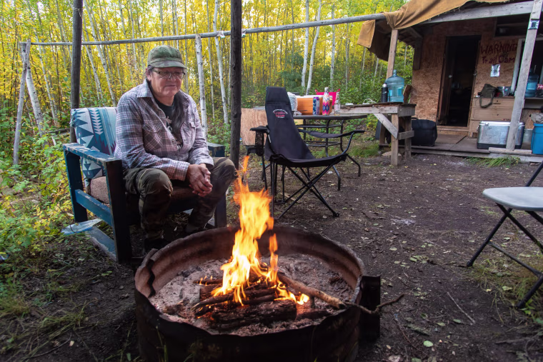 Jean L'Hommecourt warms at the fire outside the cabin she has built near the Fort McKay First Nation's village, about an hour's drive north of Fort McMurray in Alberta.
