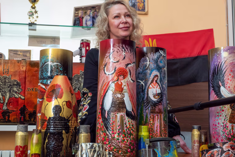 Olena Vovk stands with some of her artwork, which she created from shells and weapon cases. 