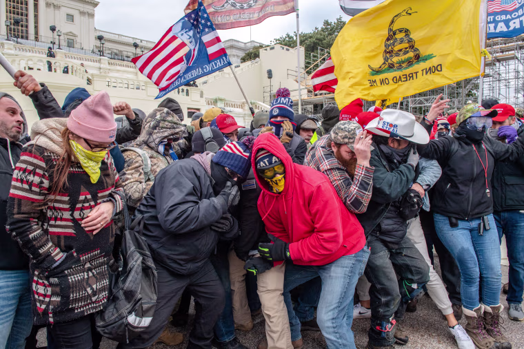 Trump supporters, including Banuelos in the white cowboy hat, react to dispersants as they protest outside of the Capitol on Jan. 6, 2021.