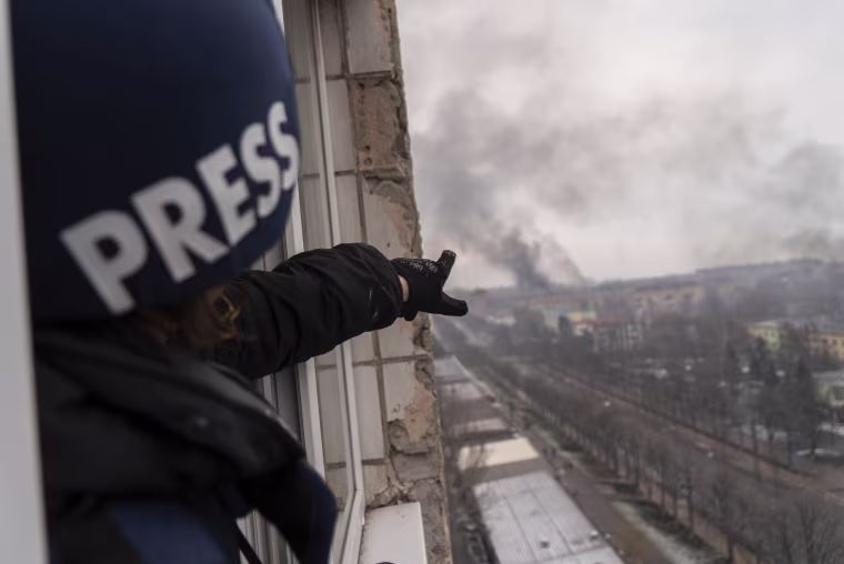 Evgeniy Maloletka points at the smoke rising after an airstrike on a Mariupol maternity hospital.