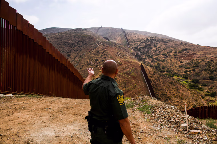 A U.S. Border Patrol agent shows an incomplete section of the new steel bollard-style border wall on a hillside along the US-Mexico border between San Diego and Tijuana on May 10, 2021, in the Otay Mesa area of San Diego County, Calif.