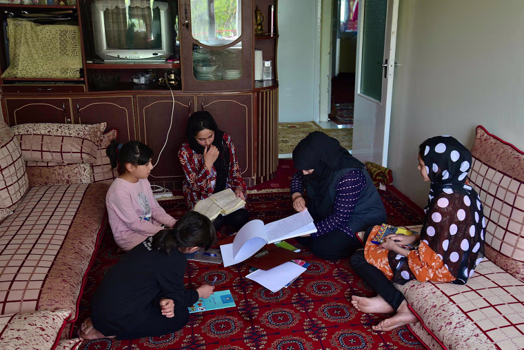 Image: School girls Malahat Haidari, right, and her sister Adeeba Haidari, center, study at their home with their younger sisters and mother in Kabul on March 24, 2022.