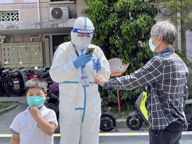 A worker in PPE scans the ID card of a man during Covid-19 screening in a residential block in Shanghai on Wednesday.