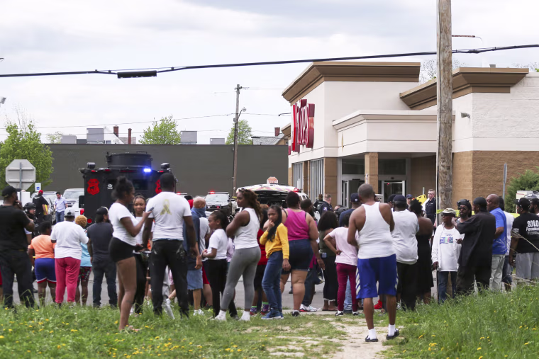 A crowd gathers as police investigate after a shooting at Tops Market