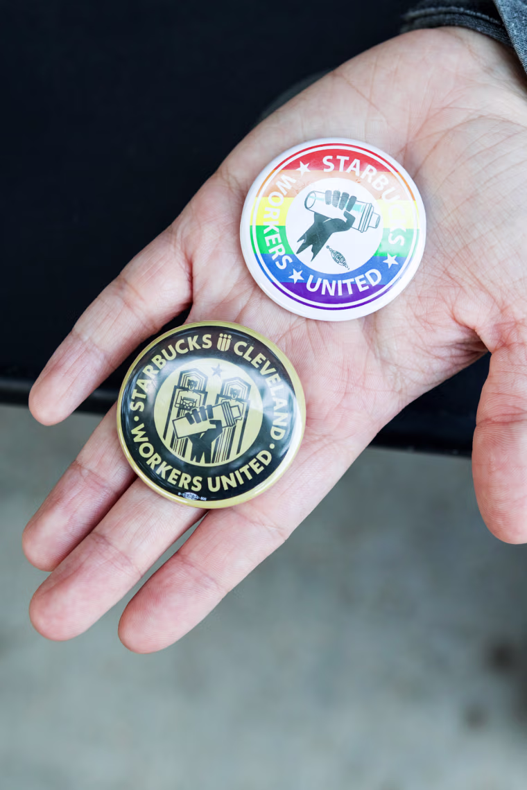 Starbucks coffee supervisor Maddie Vanhook holds Starbucks Workers United pins, in Cleveland, on May 19.