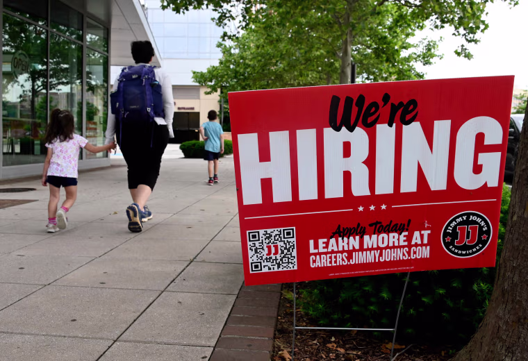 People walk past a "now hiring" sign outside a restaurant in Arlington, Va., on June 3, 2022.
