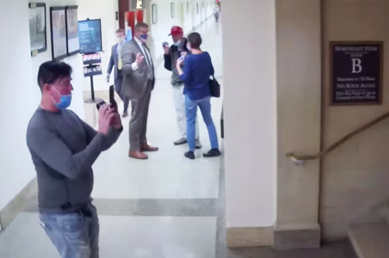Video showing the same man taking photos of hallways and staircases on the tour led by Loudermilk.