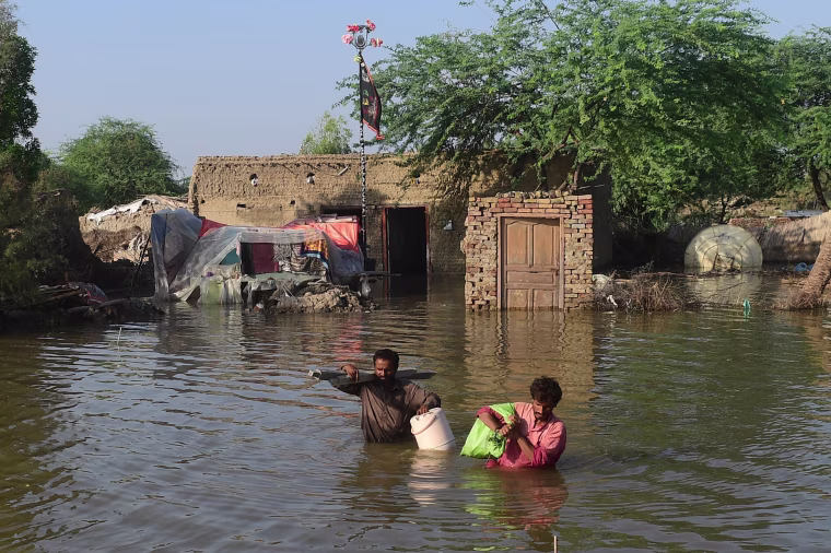 People carry belongings out from their flooded home