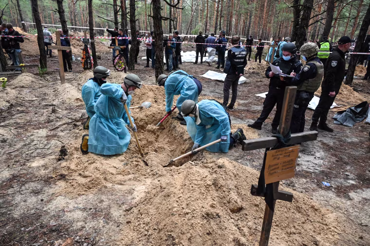 Image: Forensic technicians dig a grave in a forest on the outskirts of Izyum, eastern Ukraine on Sept. 16, 2022.