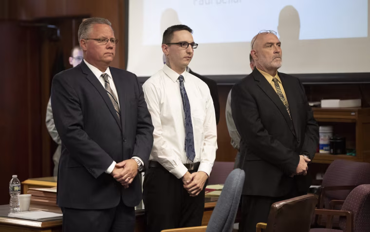 Image: Paul Bellar, center, stands before Jackson County Circuit Court Judge Thomas Wilson in Jackson, Mich. on Oct. 5, 2022.