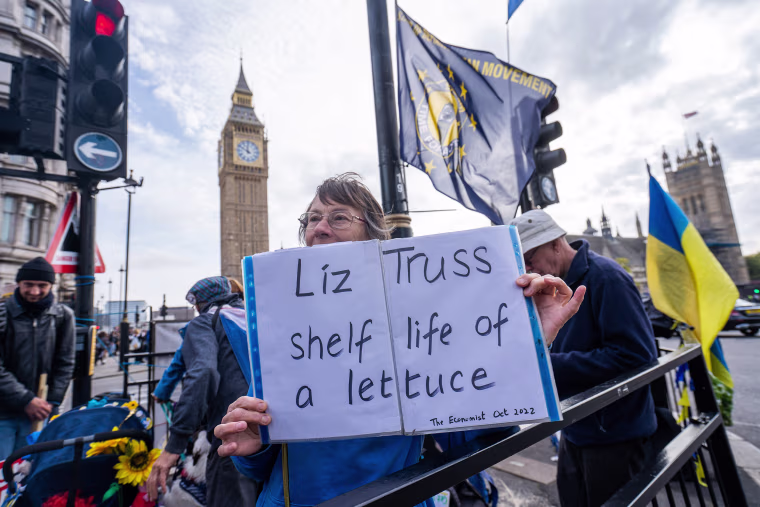 A protester holds a sign comparing Prime Minister Liz Truss to a lettuce in London on Oct. 19, 2022.