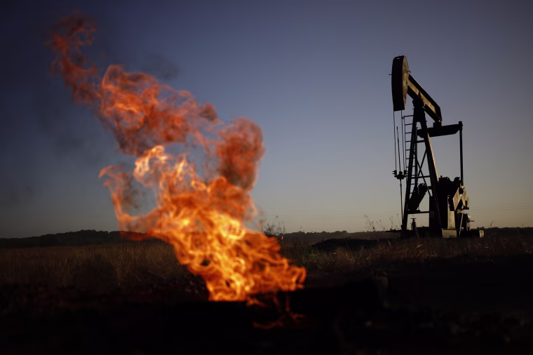 A natural gas flare burns near an oil pump jack at the New Harmony Oil Field in Grayville Illinois