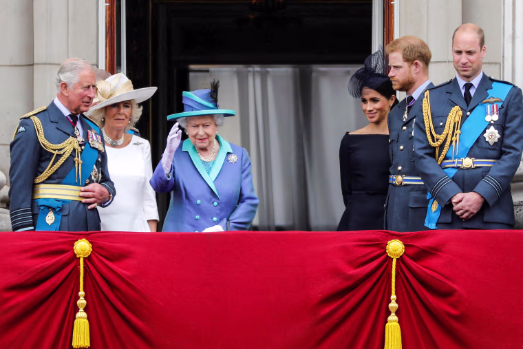 Image: Prince Charles, Prince of Wales, Camilla, Duchess of Cornwall, Queen Elizabeth II, Meghan, Duchess of Sussex, Prince Harry, Duke of Sussex and Prince William, Duke of Cambridge stand on the balcony of Buckingham Palace to watch a military fly-past to mark the centenary of the Royal Air Force (RAF) on July 10, 2018.