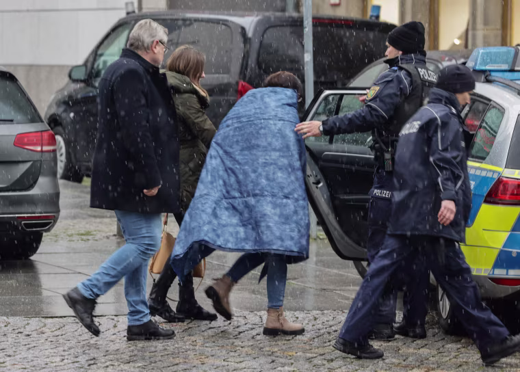 German police help a person into a police car near a shopping mall 