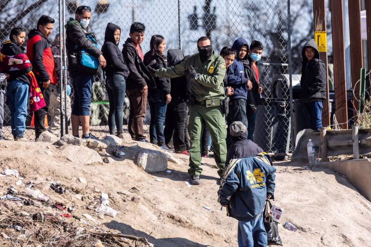 A U.S. Border Patrol agent instructs immigrants who had crossed the Rio Grande into El Paso, Texas, on Dec. 19, 2022.