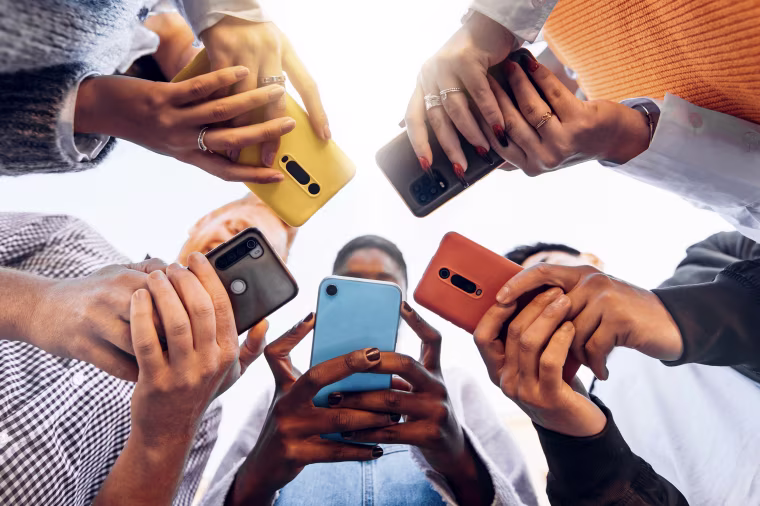 Teens in circle holding smart mobile phones - Multicultural young people using cellphones outside - Teenagers addicted to new technology concept