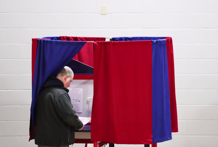 A voter prepares to cast their ballot at a polling station during the 2020 presidential primary in Manchester, N.H.