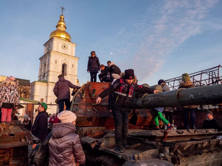 A group of children clambers over destroyed Russian military vehicles outside St Michael’s Monastery in Kyiv, Ukraine