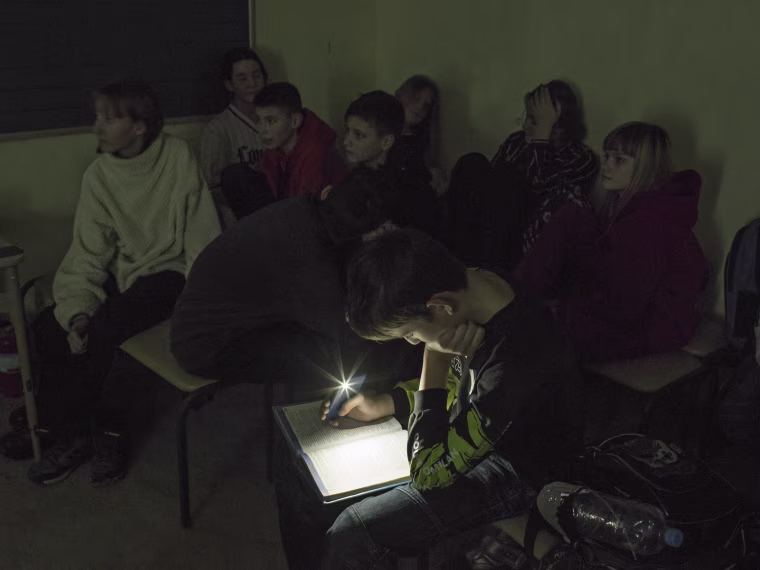 Image: A student uses light from a phone to study in a school's shelter, in Kyiv, Ukraine, Dec. 21