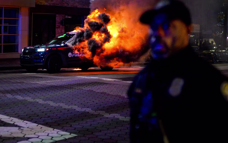 Firefighters work to extinguish a fire after an Atlanta police vehicle was set on fire during a "Stop cop city" protest in Atlanta on Jan. 21, 2023.