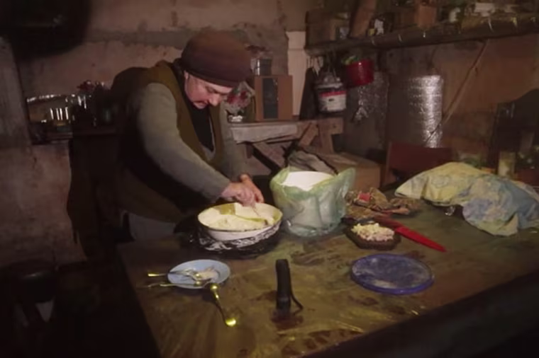 Ludmyla, 70, makes a potato cake for the people sharing her makeshift shelter in the war-torn city.