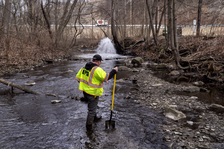 An Ohio EPA Emergency Response worker looks for signs of fish and also agitates the water in Leslie Run creek to check for chemicals that have settled at the bottom following a train derailment on Feb. 20, 2023, in East Palestine.