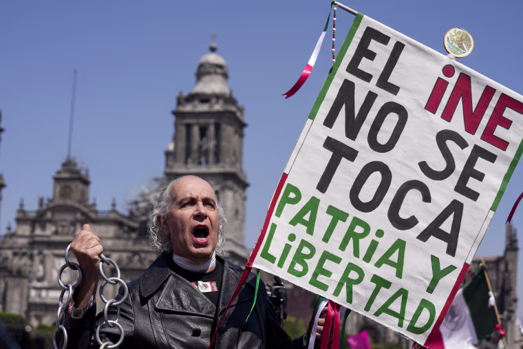 A protester dressed as independence hero Miguel Hidalgo holds a sign that reads in Spanish "Do not touch the INE, Motherland and Freedom," during a march against recent electoral reforms pushed by President Andres Manuel Lopez Obrador in Mexico City on Feb. 26, 2023.