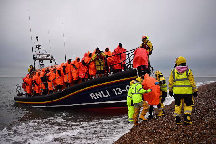 Migrants, picked up at sea attempting to cross the English Channel, are helped ashore from a Royal National Lifeboat Institution lifeboat, at Dungeness on the southeast coast of England on Dec. 9, 2022.