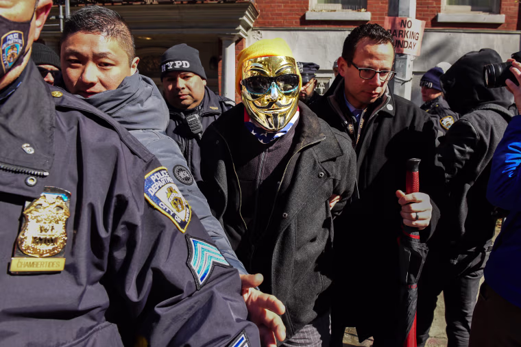  A man in a gold Anonymous mask is detained at a protest against Drag Queen story hour outside of The Center, a support space for LGBTQ+ people on March 19, 2023 in New York City. 