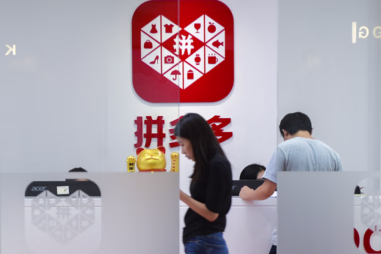 A woman walks past the reception desk at the headquarters of Pinduoduo in Shanghai on July 25, 2018. 