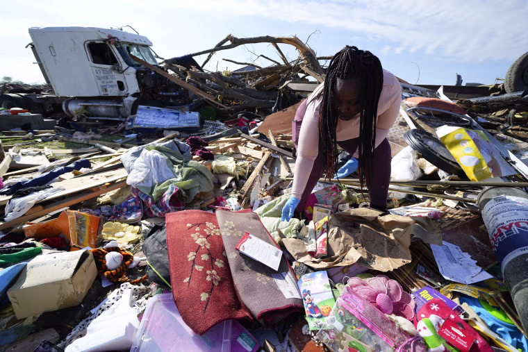Kimberly Patton surveys through the belongings at the spot of a family member's home on March 26, 2023, in Rolling Fork, Miss.