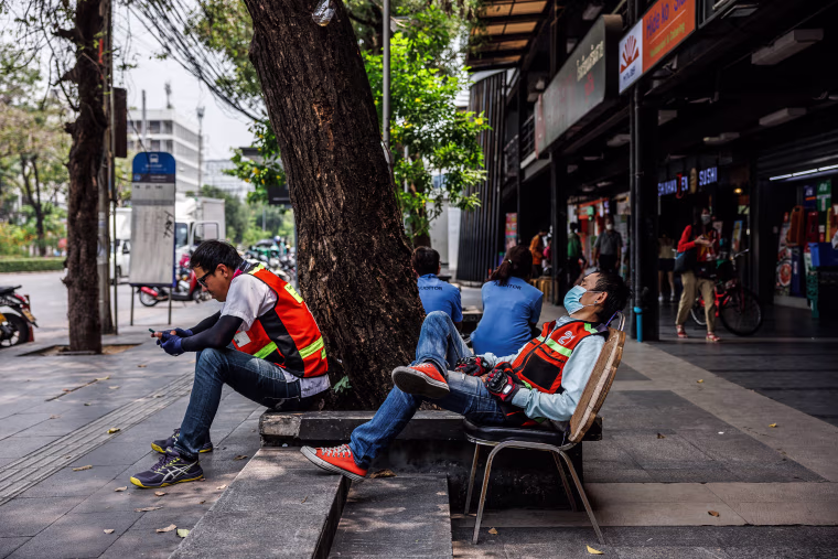 Motorbike taxi drivers rest in the shade during a heat wave in Bangkok on April 27, 2023.