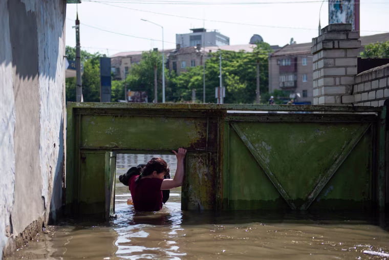 A woman ducks through a gate with an armful of her