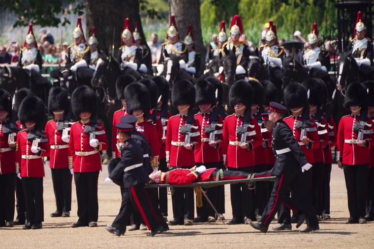 A member of the military is taken away on a stretcher by the medical team after fainting due to the heat during the Colonel's Review, for Trooping the Colour, at Horse Guards Parade in London