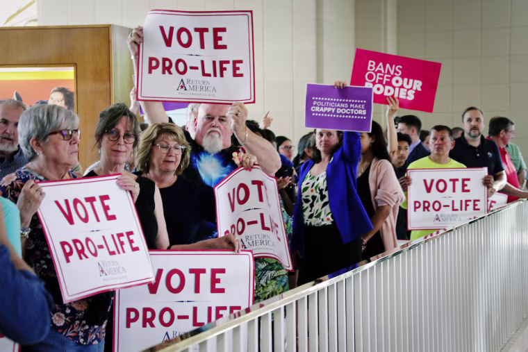 Protesters on both sides of the abortion debate hold signs May 16, 2023, in Raleigh, N.C., outside the Senate gallery.