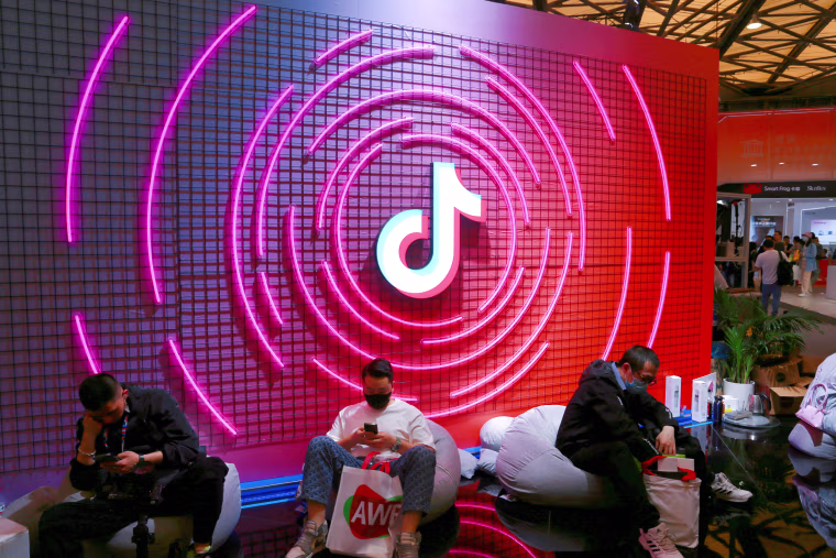 People sit in front of TikTok sign.