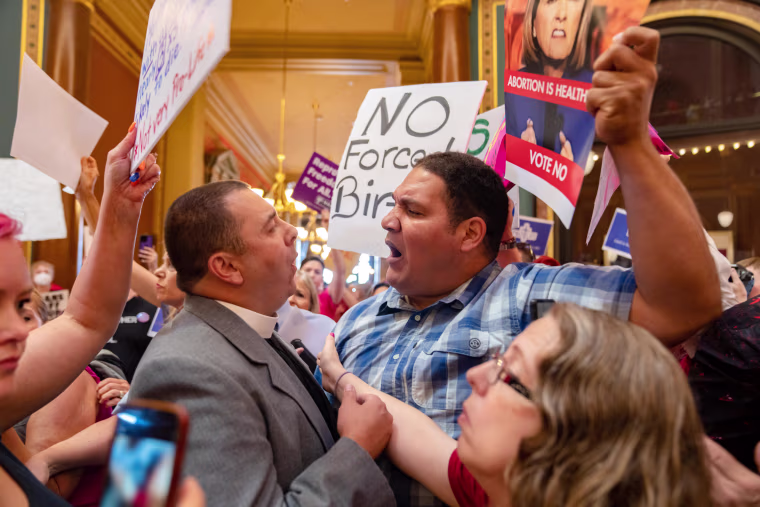 The Rev. Michael Shover of Christ the Redeemer Church in Pella, left, argues with Ryan Maher, of Des Moines as anti-abortion and abortion rights protesters clash in the Iowa Capitol rotunda on July 11, 2023.