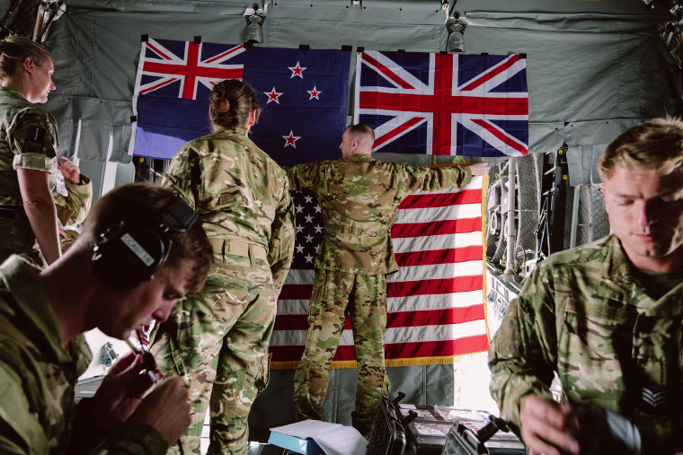 British forces hang the American flag under New Zealand and Britain's flags inside an Airbus A400M at Hickam Field in Honolulu,