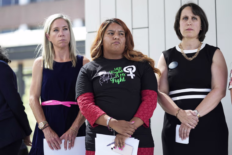 Amanda Zurawski, who developed sepsis and nearly died after being refused an abortion when her water broke at 18 weeks, left, and Samantha Casiano, who was forced to carry a nonviable pregnancy to term and give birth to a baby who died four hours after birth, center, stand with their attorney Molly Duane outside the Travis County Courthouse, Wednesday, July 19, 2023, in Austin, Texas.