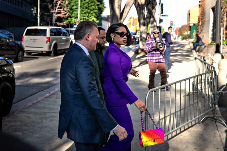 Megan Thee Stallion and two men in suits walks through barricades to enter court