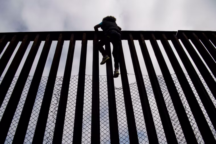 Una persona sube a lo alto del muro fronterizo en una foto de archivo de 2018 en Tijuana, México.
