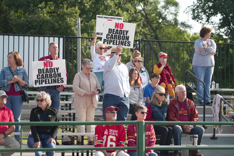 Crowd members hold up signs against the use of eminent domain to install CO2 pipelines on private land at a political rally Saturday, Sept. 9, 2023, in Nevada, Iowa.