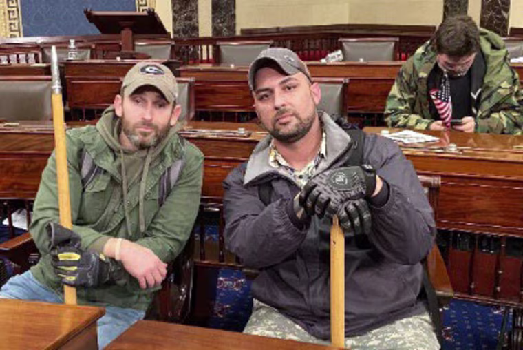 Joseph Irwin and John Richter inside the Capitol at Senate desks on Jan. 6, 2021.