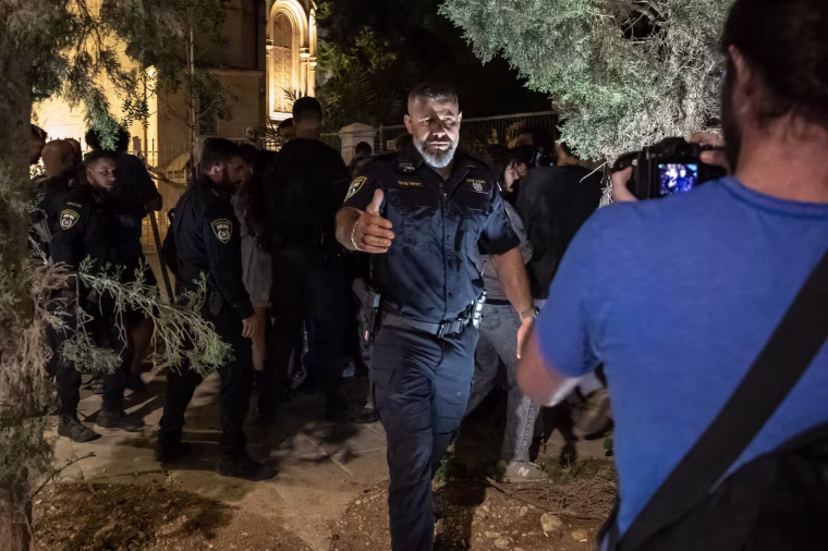 A police officer approaches a man holding a camera