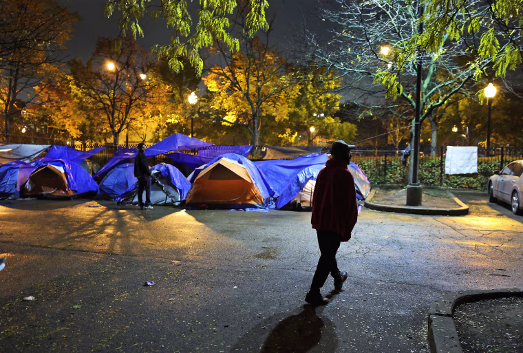Nathan McCarthy walks through a parking lot outside the 15th District police station, a space he shares with newly arrived migrants in Chicago's Austin neighborhood on Nov. 5, 2023.