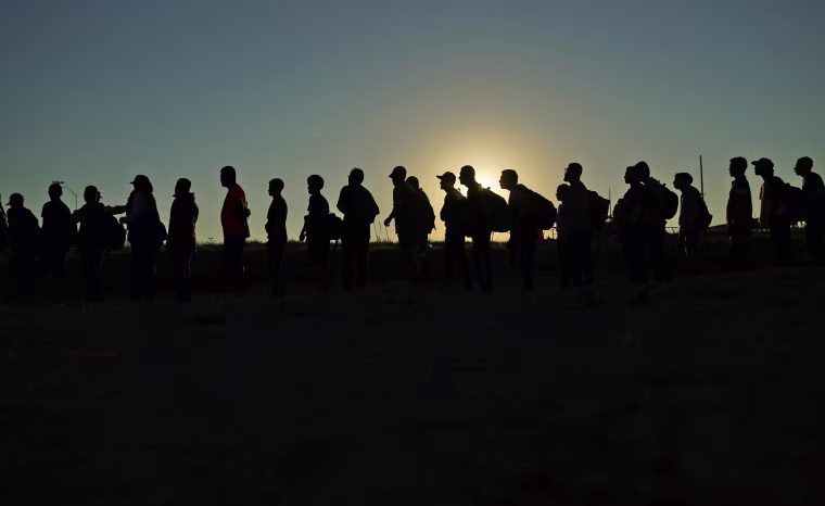 Migrants who crossed the Rio Grande and entered the U.S. from Mexico are lined up for processing by U.S. Customs and Border Protection on Sept. 23, 2023, in Eagle Pass, Texas. 